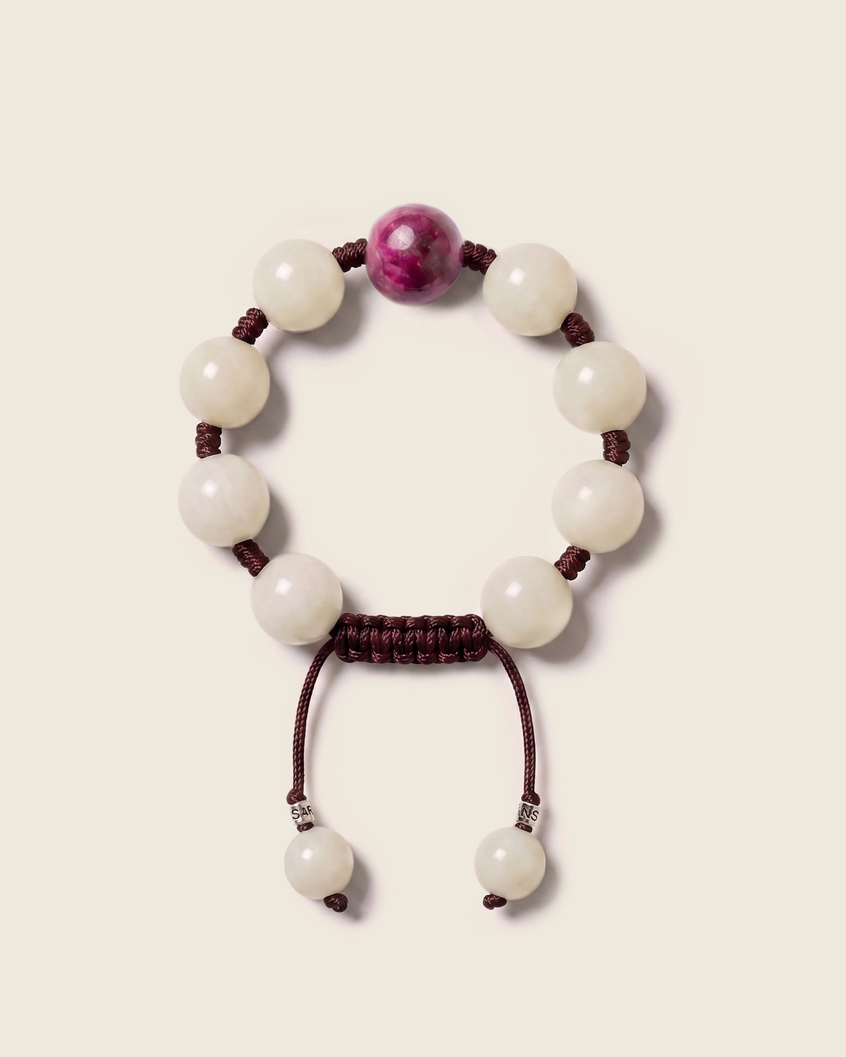 White bead bracelet with a magenta center bead and burgundy cord.