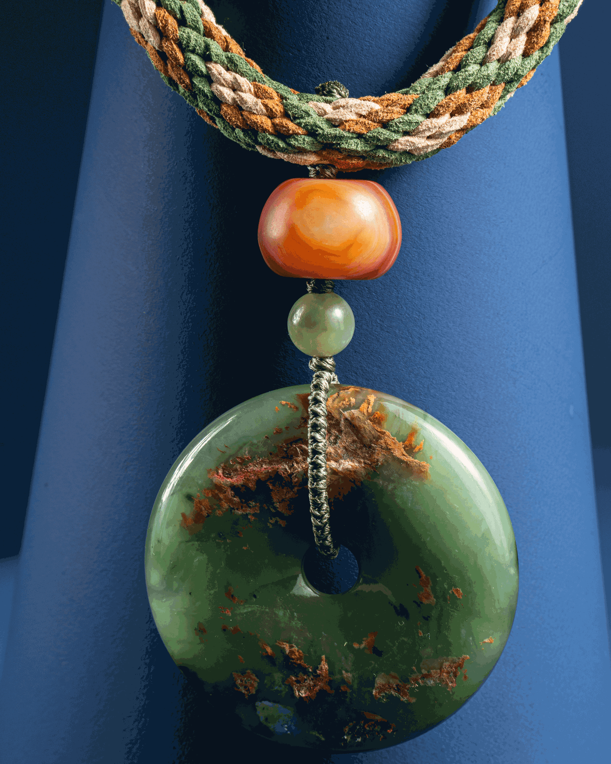 Green jade Bi disc pendant with a carnelian bead on a braided suede cord.