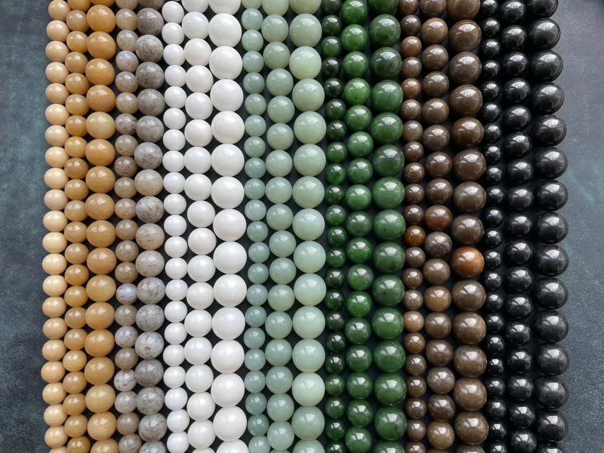 Strands of round beads sorted by color, from honey and white to green and black.