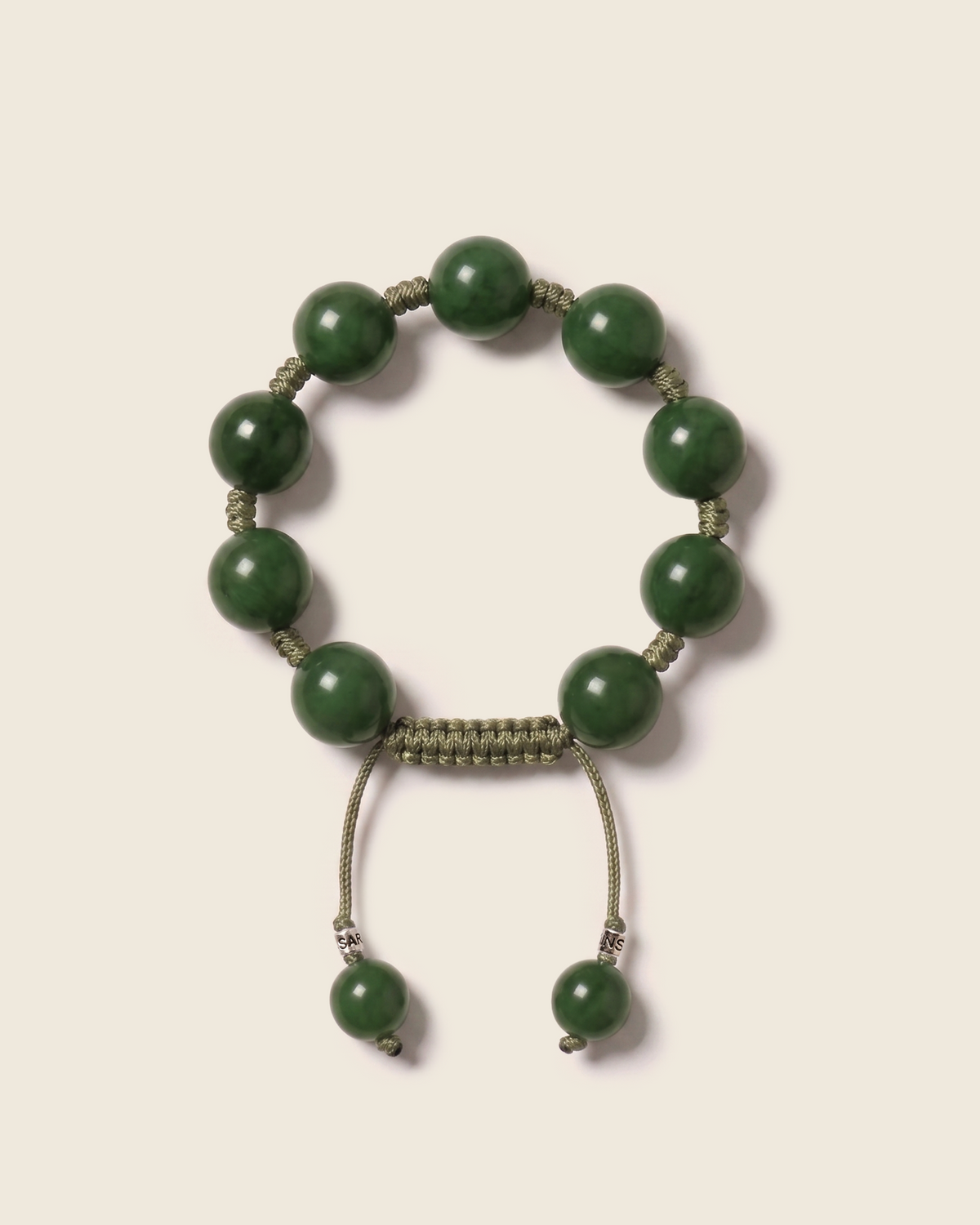 Green bead bracelet with knotted olive cord and an adjustable closure.
